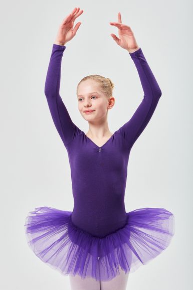 Ein junges Mädchen in einem lila Ballettbody und Tutu posiert mit erhobenen Armen in einer Ballettposition.