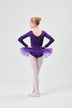 Eine Balletttänzerin in einem lila Ballettbody und Tutu steht mit den Händen in den Hüften und blickt von der Kamera weg. 4