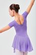 Eine junge Balletttänzerin in einem lavendelfarbenen Ballett Trikot und Rock posiert mit ausgestreckten Armen und blickt von der Kamera weg. 2