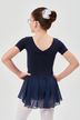 Mädchen in marineblauem Ballett-Outfit und weißen Strumpfhosen steht mit den Händen in den Hüften und blickt von der Kamera weg. 2