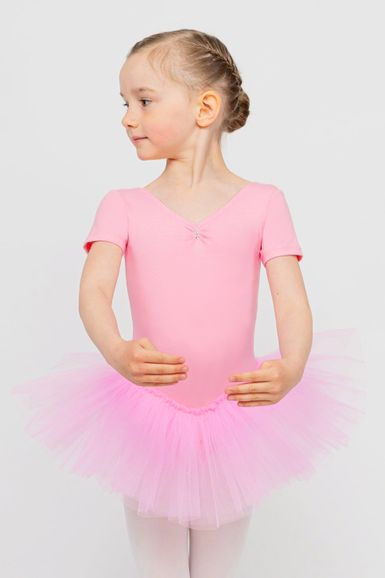 Ein junges Mädchen in einem rosa Ballett-Outfit steht in einer Ballettposition und blickt zur Seite.