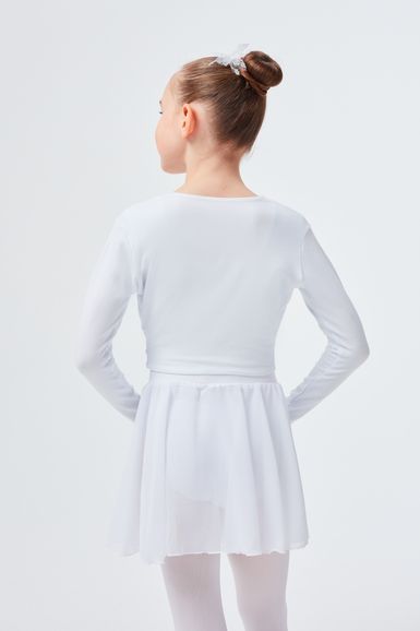 Ein junges Mädchen in einem weißen Ballett-Outfit steht mit dem Rücken zur Seite