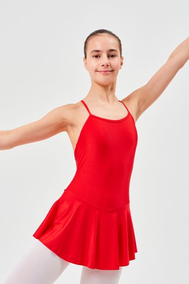Eine Balletttänzerin in einem roten Ballettbody und weißen Strumpfhosen posiert mit erhobenen Armen.
