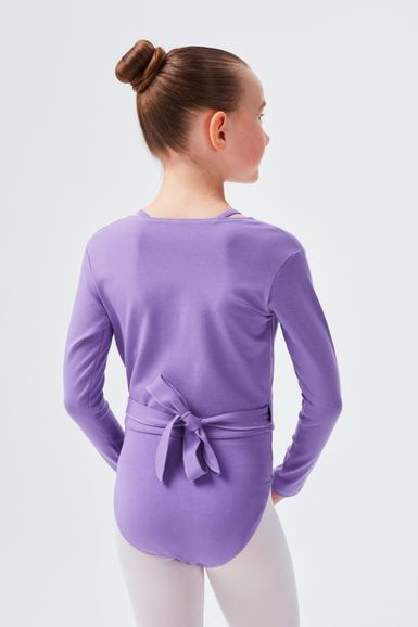Ein Mädchen in einem lila Langarmbody mit gebundenem Gürtel steht mit dem Rücken zur Seite