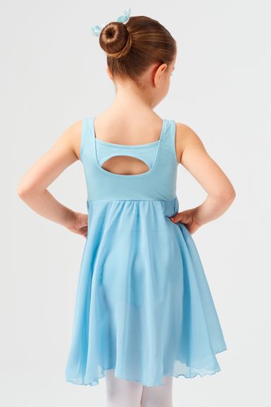 Ein junges Mädchen in einem hellblauen Ballettkleid steht mit den Händen in den Hüften und blickt von der Kamera weg.