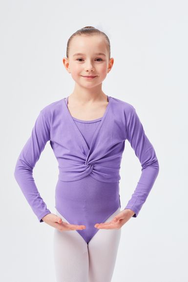 Ein junges Mädchen in einem lila Tanzoutfit und weißen Strumpfhosen steht mit den Händen in Ballettposition.