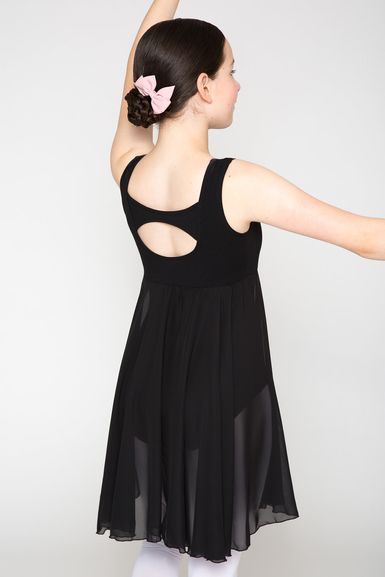 Mädchen in einem schwarzen Tanzkleid mit einer rosa Haarschleife posiert mit erhobenen Armen und blickt von der Kamera weg.