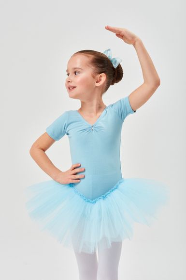 Ein junges Mädchen in einem hellblauen Ballett-Outfit posiert mit einem erhobenen Arm