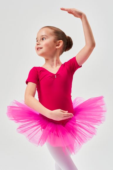 Ein junges Mädchen in einem rosa Ballett Trikot und Tutu posiert in einer Balletthaltung.