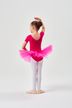 Ein junges Mädchen in einem rosa Ballett Trikot und Tutu steht in einer Ballettpose mit dem Gesicht abgewandt. 4