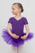 Junges Mädchen in einem lila Ballett Trikot und Tutu posiert in einer Ballettposition vor einem schlichten grauen Hintergrund. 1