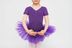 Ein Kind in einem lila Ballett Trikot und Tutu steht mit vor dem Körper ausgestreckten Armen. 5