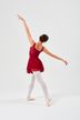 Eine Balletttänzerin in einem roten Kleid und weißen Strumpfhosen posiert mit einem erhobenen Arm und dem anderen zur Seite ausgestreckt auf einem weißen Hintergrund. 4