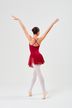Eine Balletttänzerin in einem roten Kleid und weißen Strumpfhosen posiert auf Spitze mit erhobenen Armen und blickt von der Kamera weg. 4