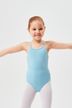 Ein junges Mädchen in einem hellblauen Ballettbody und weißen Strumpfhosen steht mit ausgestreckten Armen. 1