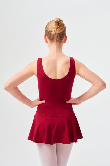 Ein Mädchen in einem roten Ballett Trikot und Rock steht mit den Händen in den Hüften und dem Rücken zur Kamera.