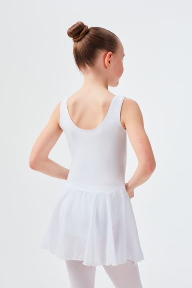 Mädchen in weißem Ballett Trikot und Rock steht mit den Händen in den Hüften und dem Rücken zur Kamera.