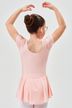 Ein junges Mädchen in einem rosa Ballettbody und einem Ballettdutt posiert mit erhobenen Armen 2