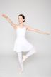 Eine junge Balletttänzerin in einem weißen Ballett Trikot und Rock posiert mit einem erhobenen Bein und ausgestreckten Armen in einem Studio. 3