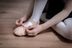 Eine Person im Ballettkostüm sitzt auf einem Holzboden und bindet das Band an einem rosa Ballettschuh fest. 7