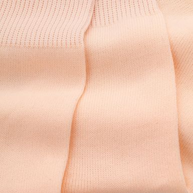Nahaufnahme eines blassrosa Strickstoffs mit sichtbaren gerippten und glatt strukturierten Abschnitten.