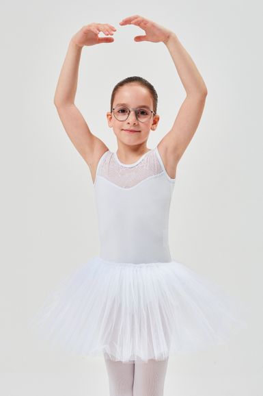 Kind und weißem Ballettoutfit posiert mit erhobenen Armen.