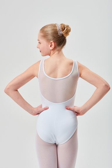 Eine junge Balletttänzerin in einem weißen Ballett Trikot steht mit den Händen in den Hüften und blickt von der Kamera weg.
