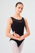 Eine junge Frau in einem schwarzen Ballett Trikot und weißen Strumpfhosen posiert mit verschränkten Armen in einer Ballettposition. 1