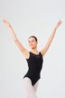 Eine Balletttänzerin in einem schwarzen Ballett Trikot und weißen Strumpfhosen posiert mit erhobenen Armen. 3