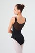 Eine Ballerina in einem schwarzen Ballett Trikot und weißen Strumpfhosen steht mit dem Rücken zu ihm und blickt über ihre Schulter. 2