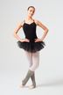 Eine Ballerina in einem schwarzen Ballett Trikot und Tutu posiert mit den Armen in den Hüften und trägt weiße Strumpfhosen und graue Beinwärmer. 2