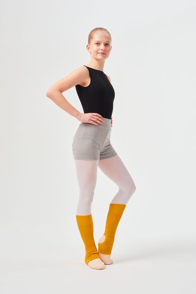 Eine Person in Tanzkleidung steht mit den Händen in den Hüften und trägt einen schwarzen Ballettanzug