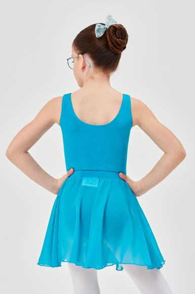 Ein Mädchen in einem blauen Ballett Trikot und Rock steht mit den Händen in den Hüften und blickt von der Kamera weg.