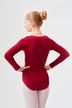 Eine junge Frau in einem roten Ballett Trikot und weißen Strumpfhosen steht mit abgewandtem Gesicht und den Händen in den Hüften. 2