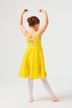Ein junges Mädchen in einem gelben Kleid und Ballettschuhen posiert mit erhobenen Armen und dem Gesicht abgewandt. 2