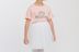 Ein Kind in einem rosafarbenen Little Ballerina-T-Shirt und einem weißen Tutu steht. 4