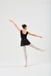 Eine Balletttänzerin in einem schwarzen Ballett Trikot und Rock balanciert mit ausgestreckten Armen auf einem Bein und blickt auf einen schlichten weißen Hintergrund. 4