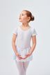 Ein junges Mädchen in einem weißen Ballett-Outfit steht mit gefalteten Händen da und blickt nach oben. 1