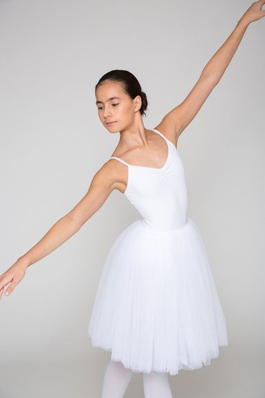 Balletttänzerin in einem weißen Ballett Trikot und Tutu posiert mit anmutig ausgestreckten Armen.