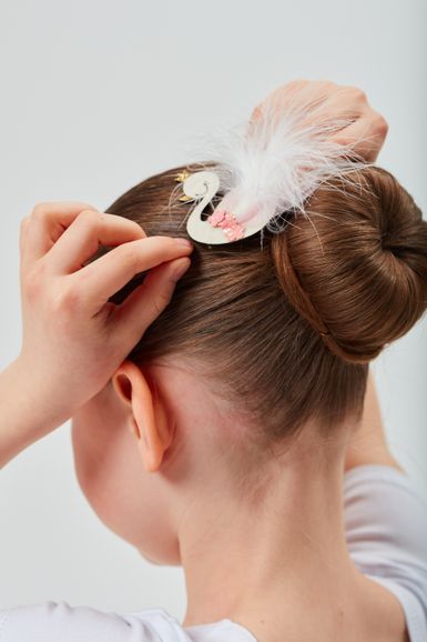 Ein Mädchen befestigt einen Dutt im Haar mit einer dekorativen