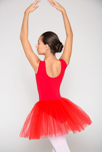 Eine Ballerina in einem roten Trikot und Tutu steht mit erhobenen Armen auf Spitze und blickt von der Kamera weg.