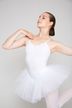 Eine Balletttänzerin in einem weißen Tutu posiert mit einem erhobenen Arm und dem anderen in der Nähe ihrer Schulter gebogen. 1