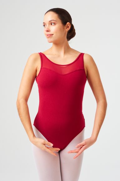 Eine Balletttänzerin in einem roten Trikot und weißen Strumpfhosen steht in einer Ballettpose.