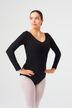 Eine Balletttänzerin in einem schwarzen Langarmbody und einer leichten Strumpfhose steht mit den Händen in den Hüften.