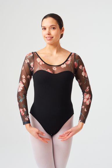 Frau trägt einen schwarzen Leotard mit transparenten Ärmeln mit Blumenmuster und helle Strumpfhosen und steht in einer Ballettpose.