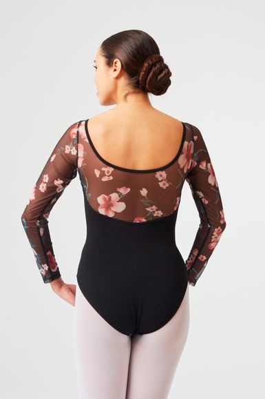 Frau in einem schwarzen Trikot mit geblümten Netzärmeln und rosa Strumpfhosen