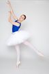 Eine Balletttänzerin in einem blauen Trikot und einem weißen Tutu führt eine Ballettpose auf Spitze aus.