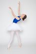 Balletttänzerin im blauen Trikot und weißen Tutu posiert auf Spitze mit erhobenen Armen.