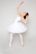 Eine Ballerina in einem weißen Tutu steht mit erhobenen Armen auf Spitze und posiert.