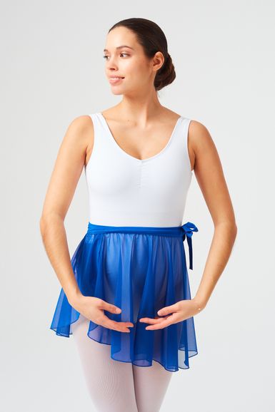 Eine Frau in einem weißen Trikot und einem blauen Ballettrock steht in einer Ballettpose.